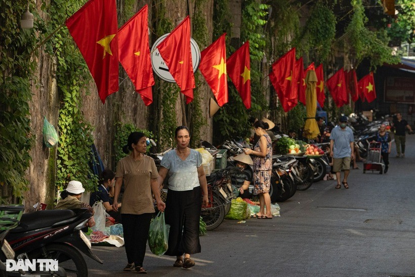 Phố Gầm Cầu (quận Hoàn Kiếm) mỗi buổi sáng sớm nhộn nhịp với chợ dân sinh, trở nên nổi bật với hàng cờ đỏ sao vàng treo dọc lối đi.