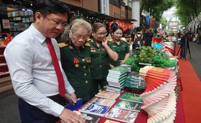 Các đại biểu tham quan triển lãm, giới thiệu các tác phẩm viết về lực lượng Quân đội nhân dân Việt Nam. (Ảnh: Báo Tin tức)