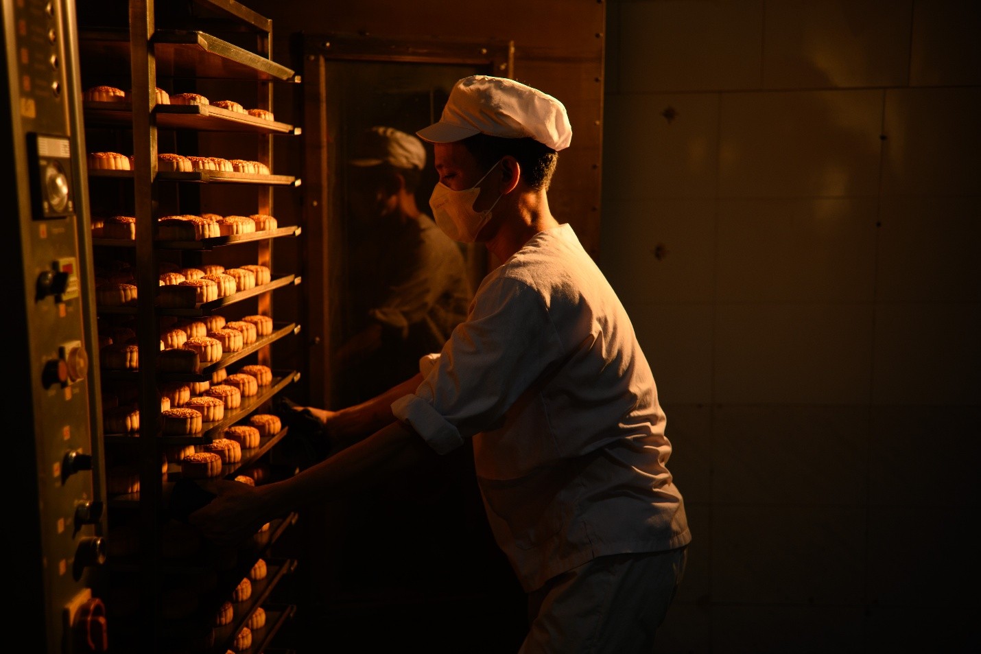 A person in a white hat and white uniform putting food into a rackDescription automatically generated
