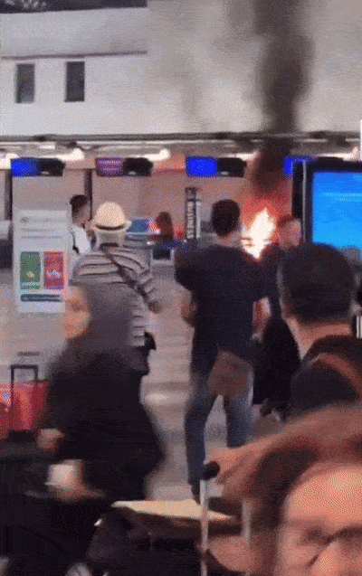 ezgif-69eb38bd0559a8-hammer-wielding-man-sets-check-in-desk-on-fire-at-italy-airport-passengers-flee-in-panic-1756259575.gif